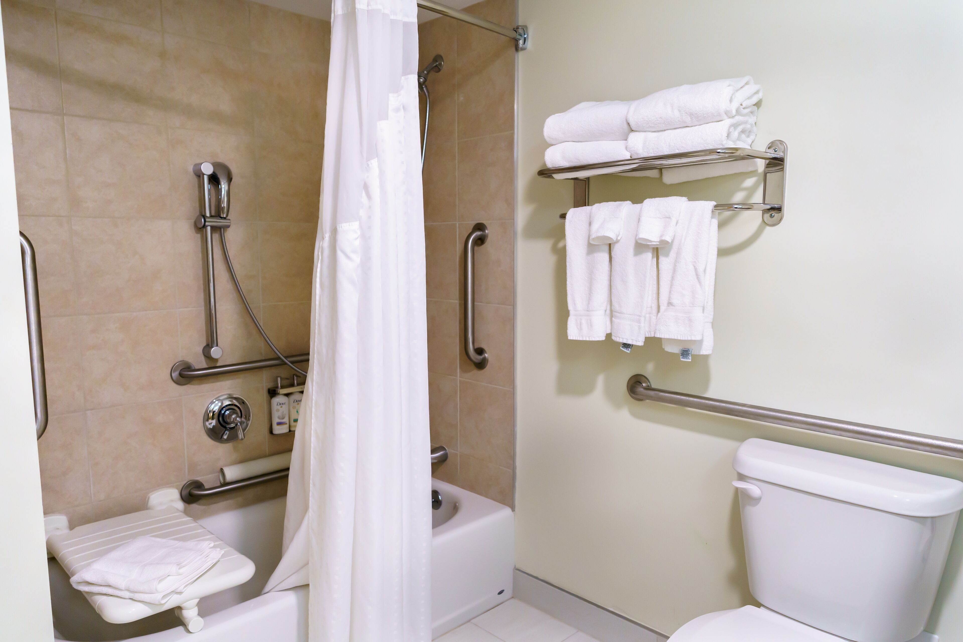 A bathroom with a shower, toilet, and a shelf with towels.