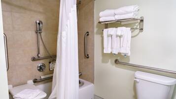 A bathroom with a shower, toilet, and a shelf with towels.