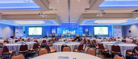 A conference room with multiple tables and chairs, a stage with a presentation screen, and a banner reading 'AFloat American Floating Offshore Wind Technical Summit'.