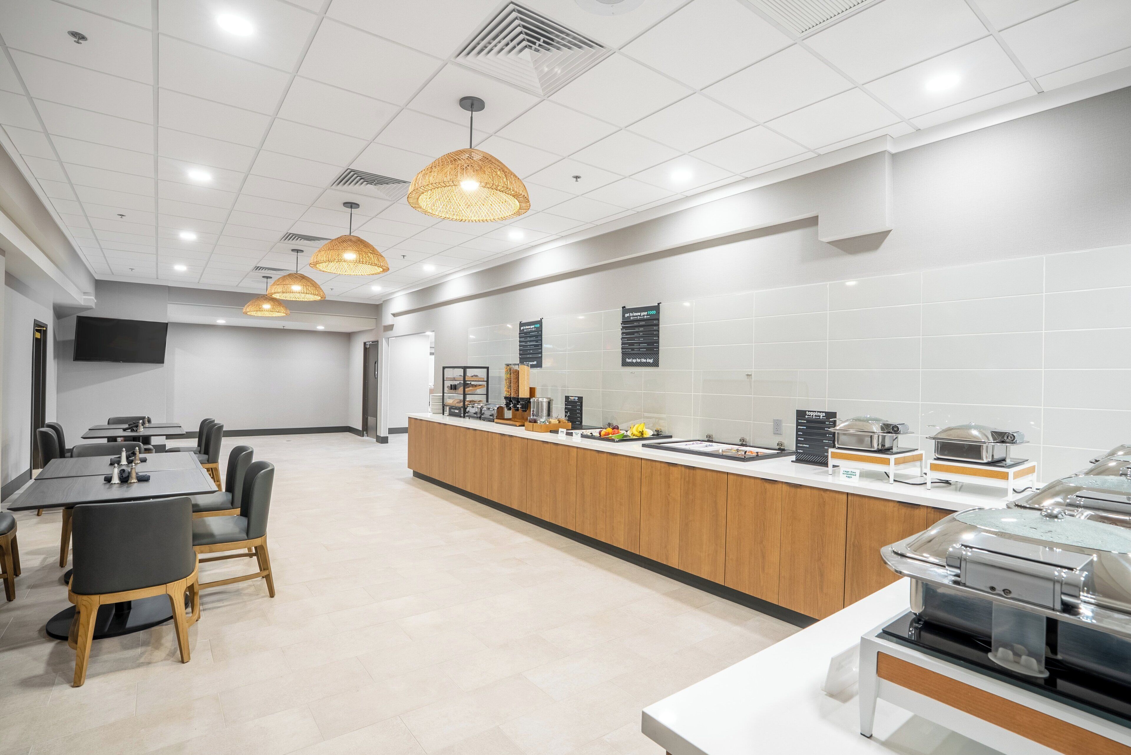 Eine moderne Küche mit einer langen Theke, einem Buffetservice und einer Sitzecke mit Tischen und Stühlen.
