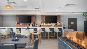 A modern bar area with a long counter, multiple seating options, and a built-in fire feature. - Holiday Inn Portland-By the Bay by IHG (Portland)