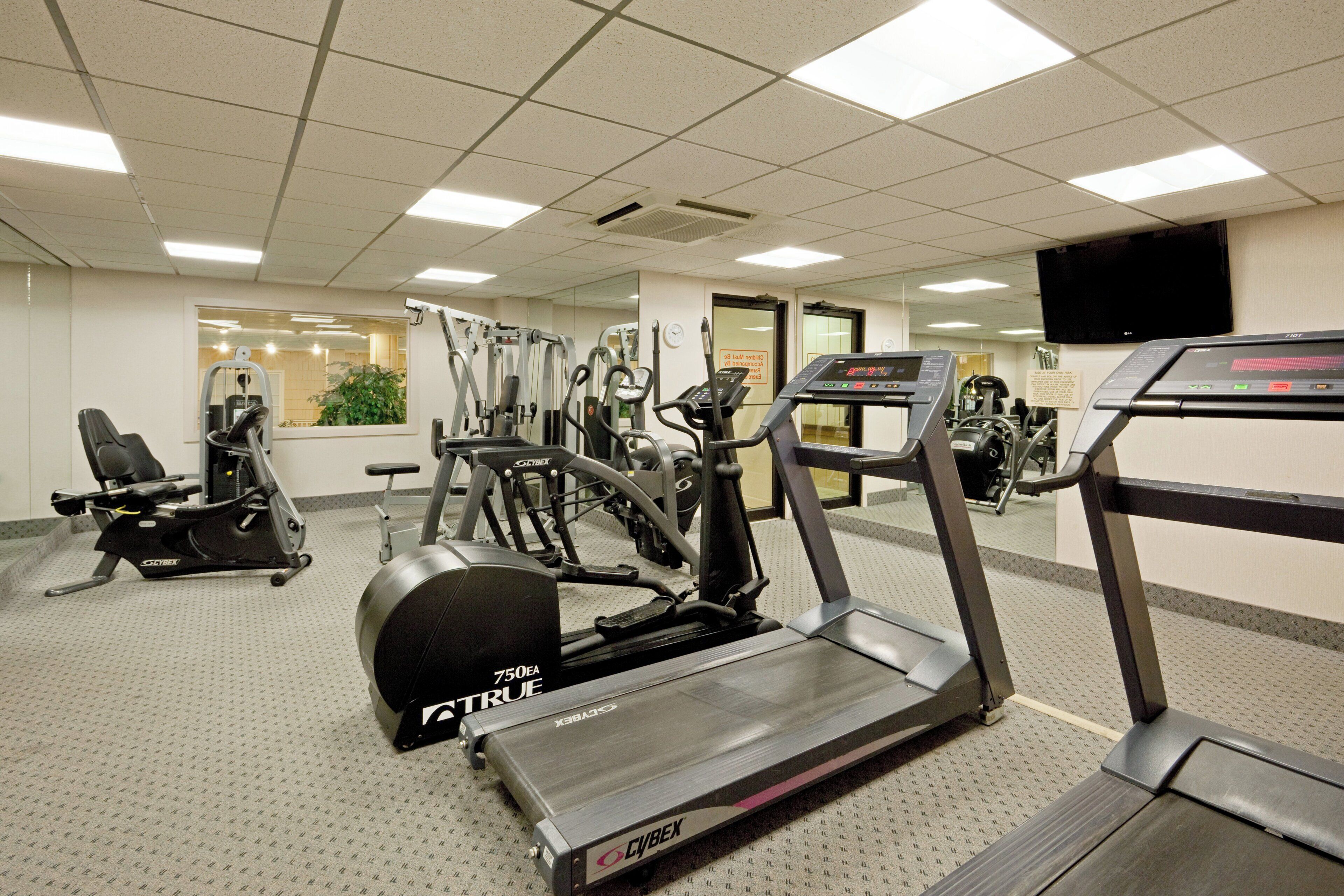 Une salle de sport équipée de divers appareils d’exercice, notamment des tapis de course, des vélos d’appartement et des appareils de musculation.