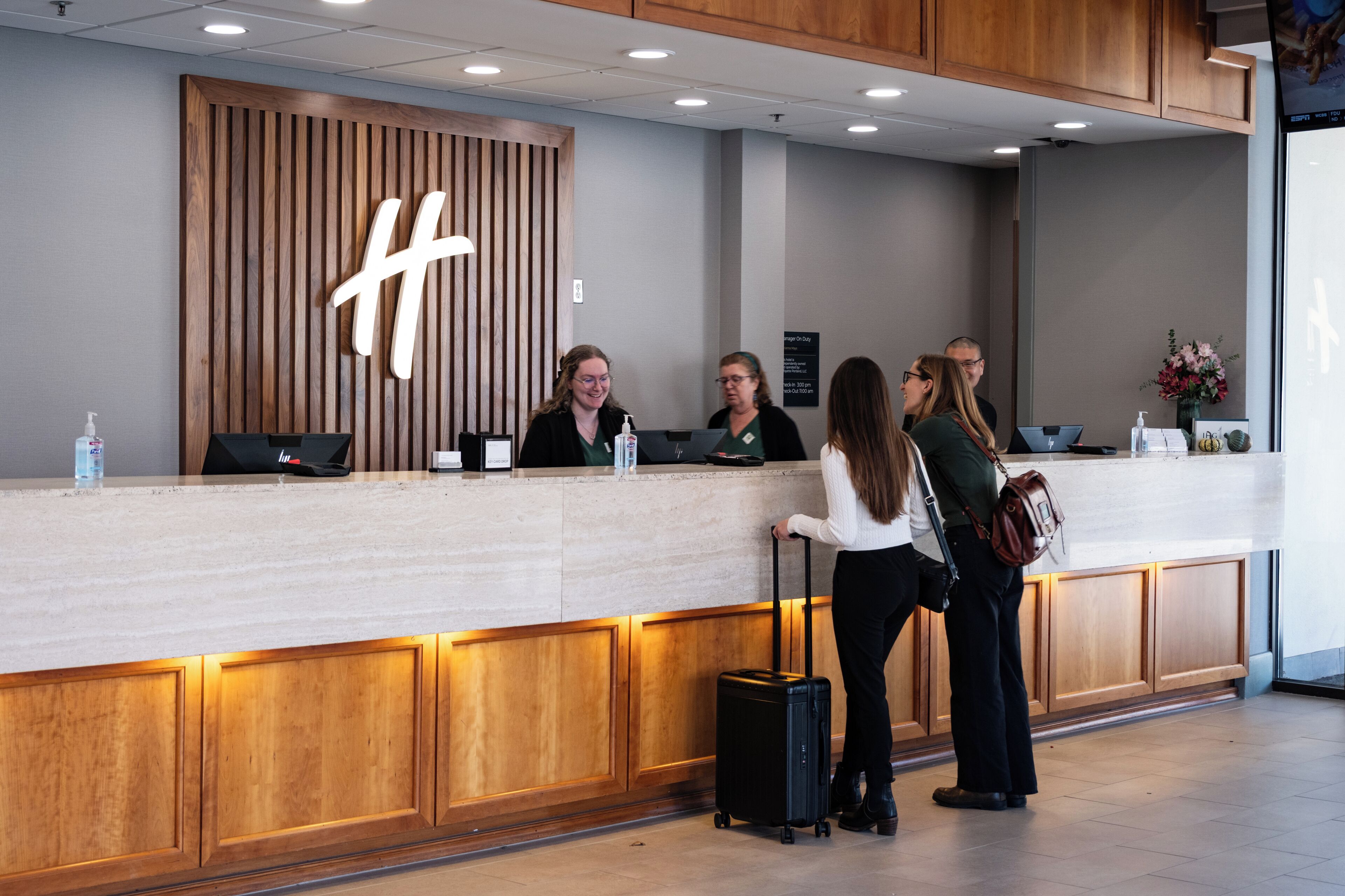 En receptionsdisk med en träpaneldesign och en stor logotyp i form av bokstaven ”H”.
