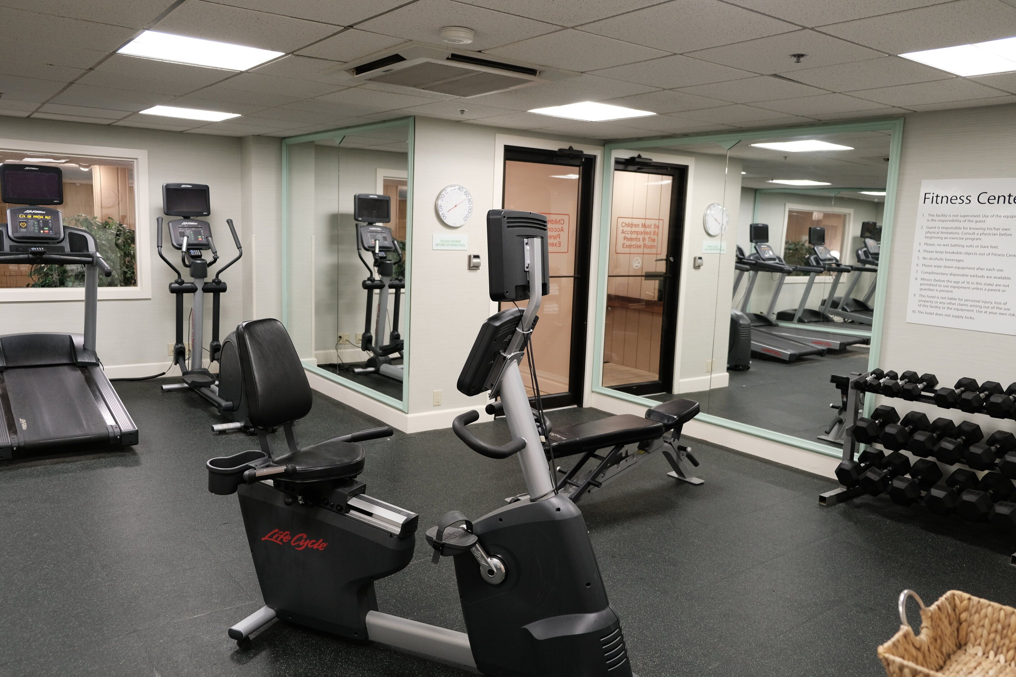 A gym with cardio machines, weight benches, and dumbbells.