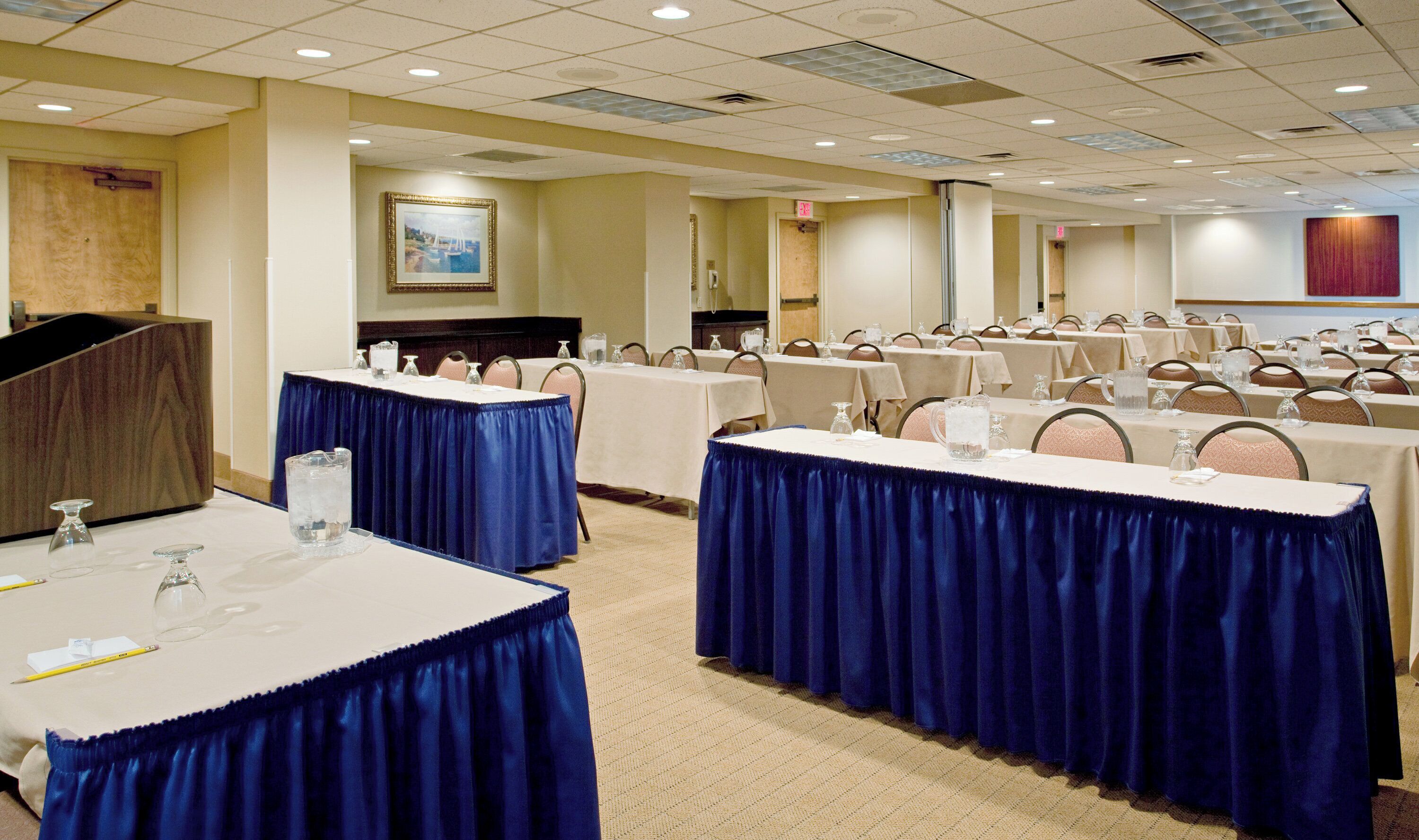 A conference room with tables set for a meeting, equipped with chairs and water pitchers.