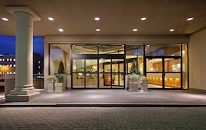 A hotel entrance with a glass door, a column, and potted plants.