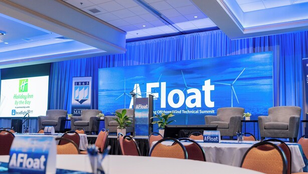 Un salón de conferencias con una pantalla grande que muestra 'AFloat' y 'Holiday Inn by the bay'.