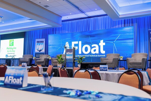 Une salle de conférence dotée d’un grand écran affichant les logos « AFloat » et « Holiday Inn by the bay ».