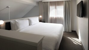A hotel room with a large bed, a bedside table, a flat-screen TV mounted on the wall, and a window with curtains. - Residence Inn By Marriott Boulder (Boulder)