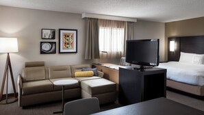 A hotel room with a sofa, a small table, a TV, a bed, and artwork on the wall. - Residence Inn By Marriott Boulder (Boulder)