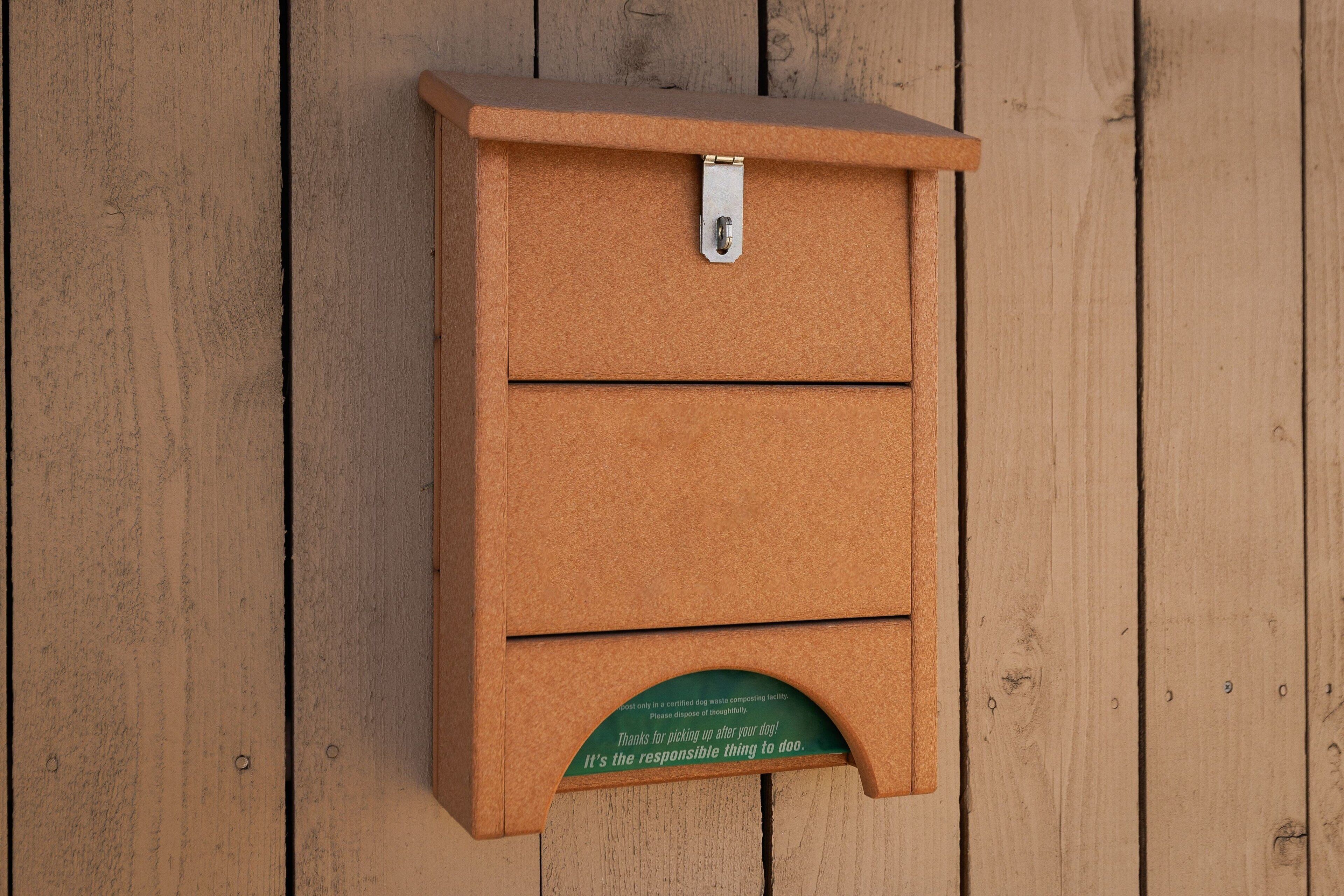 A brown, rectangular, wall-mounted box with a metal latch and a green sign at the bottom.