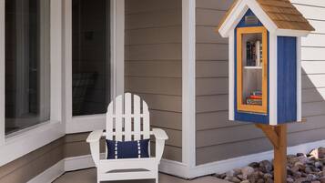 Relax in a comfortable Adirondack chair on the porch, surrounded by a selection of books on a nearby bookcase.