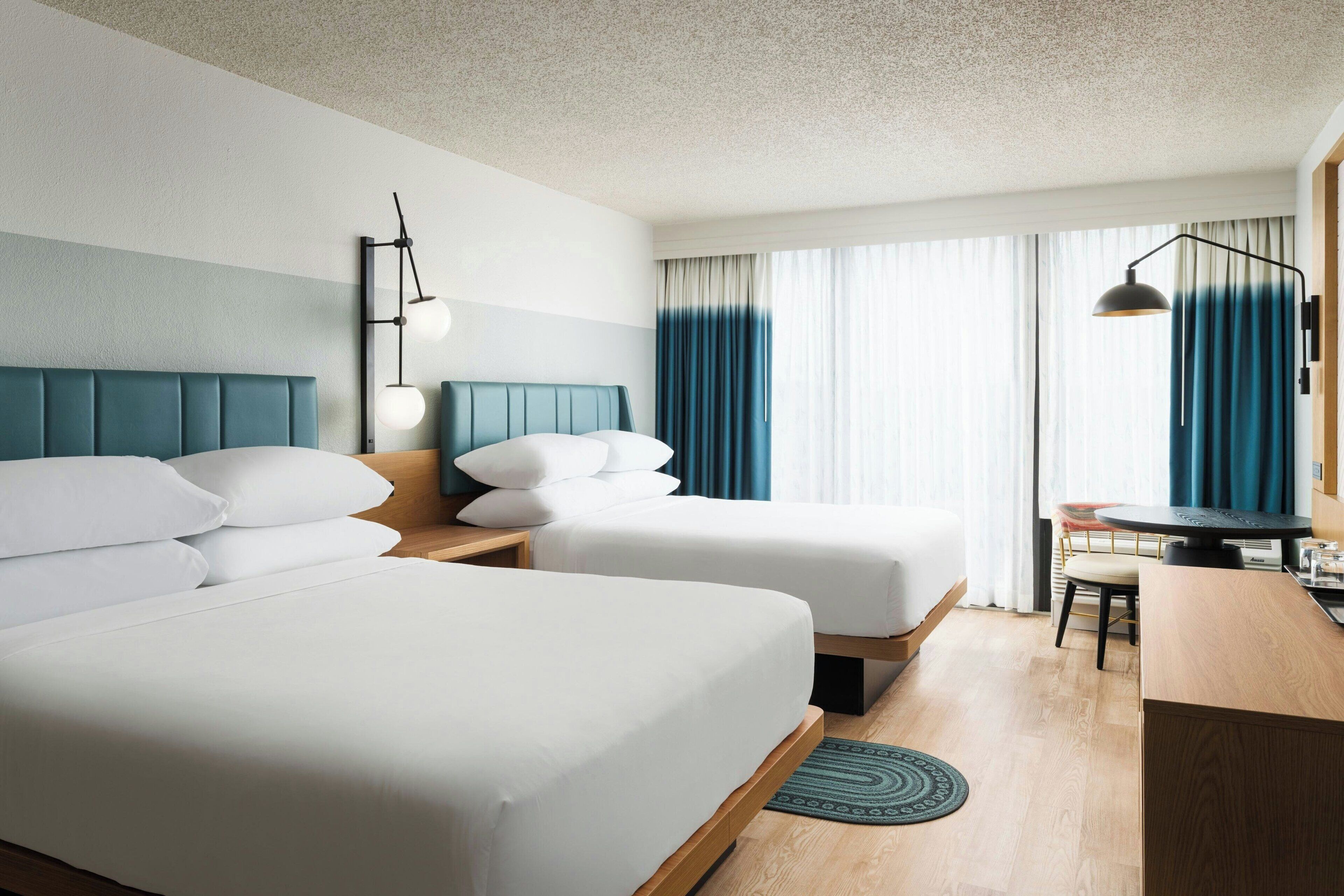 Une chambre d’hôtel avec deux lits, un bureau et une chaise.
