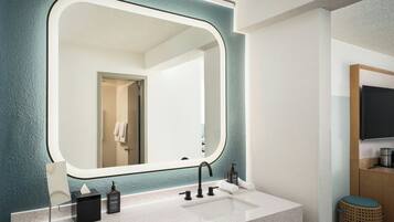 Een moderne badkamer met een grote spiegel, een wit wastafelmeubel en een houten kast.