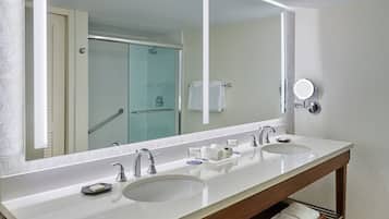 A modern bathroom with a double sink, a large mirror, and a glass shower enclosure.