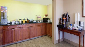 A hotel kitchen with wooden cabinets, a coffee station, and a buffet area.