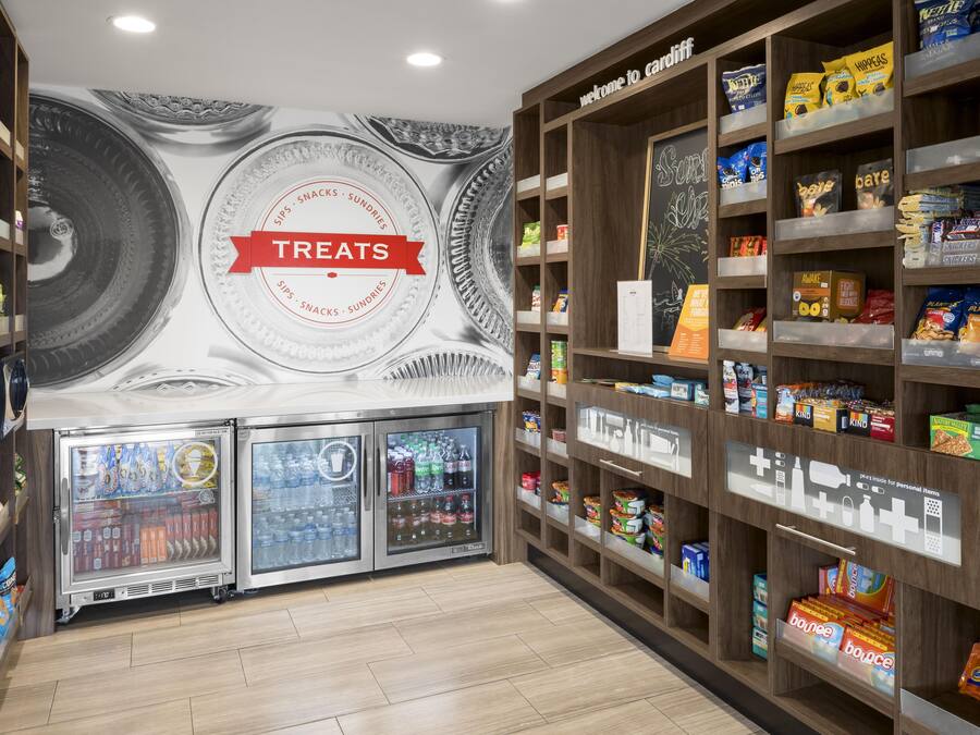 A snack and beverage area with a 'Treats' sign, shelves stocked with snacks, and a beverage dispenser.