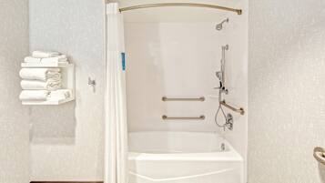 A modern bathroom with a walk-in shower, grab bars, and a towel rack.