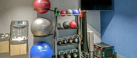 A gym with exercise equipment, a water dispenser, and a television.