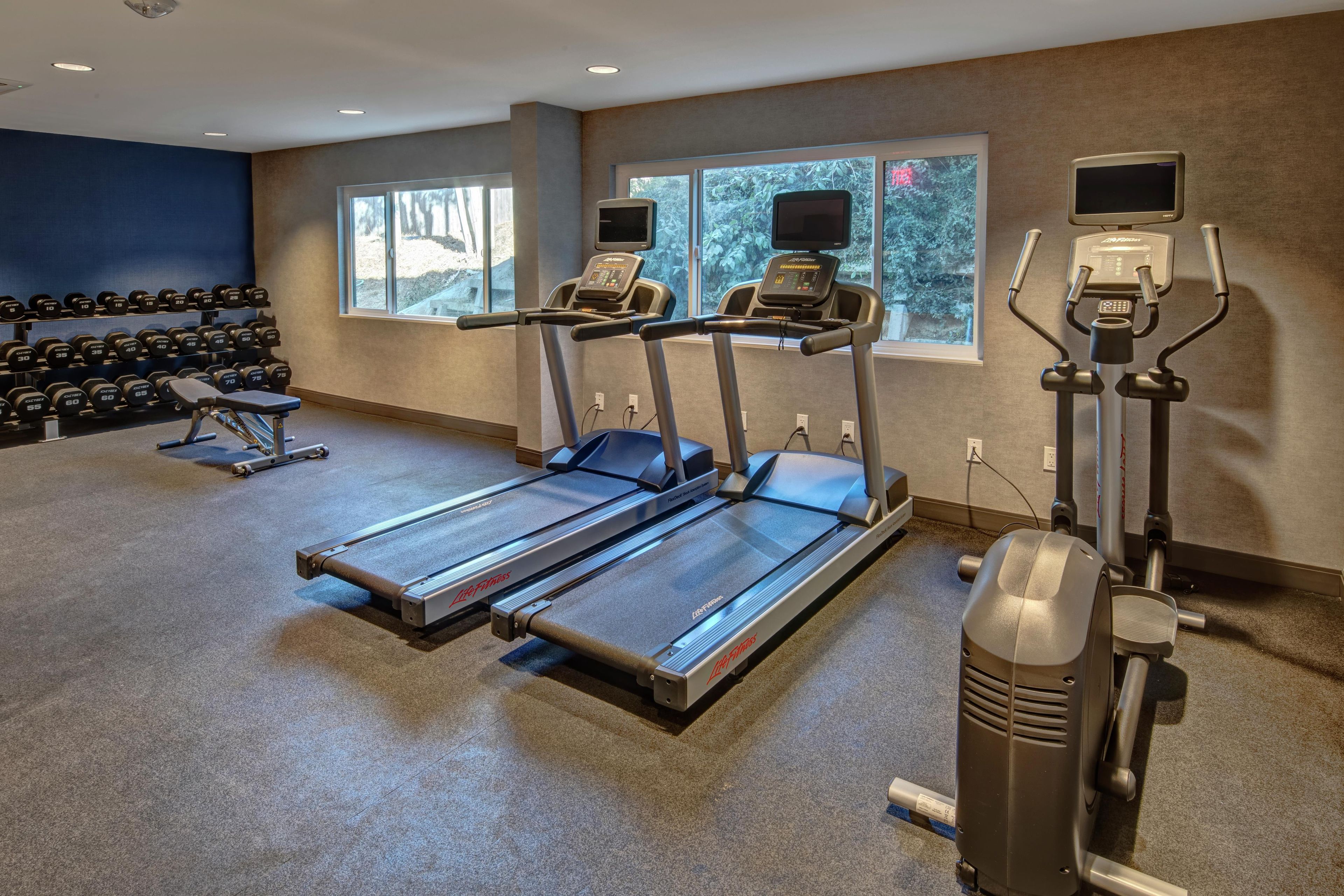 Une salle de sport équipée de tapis de course, d’haltères et de vélos d’exercice.