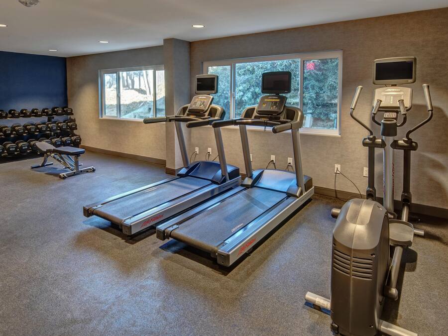 Une salle de sport équipée de tapis de course, d’haltères et de vélos d’exercice.