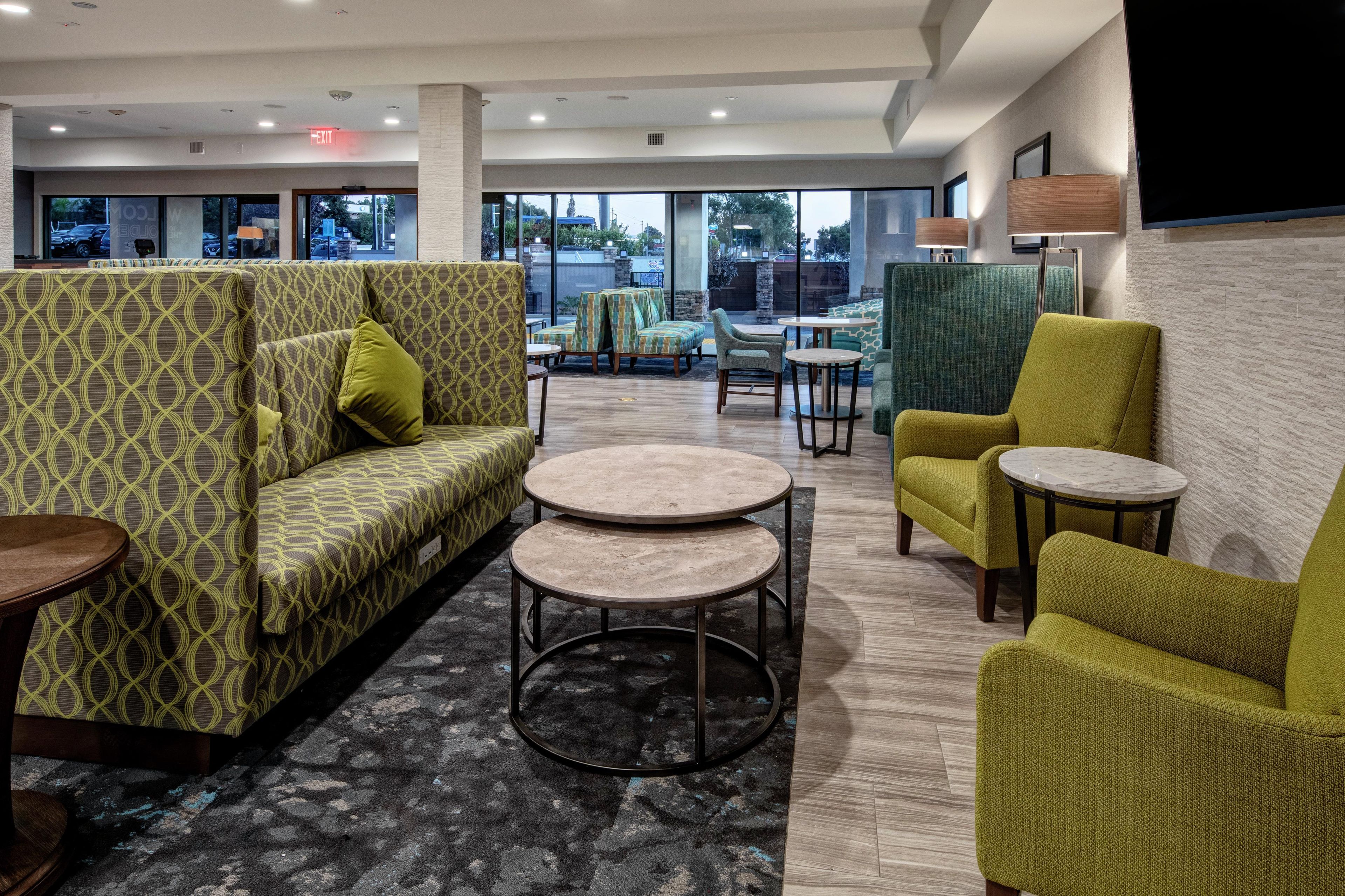A hotel lobby with a patterned sofa, round tables, and chairs.