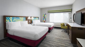 A hotel room with two beds, a desk, a chair, a television, and a window with blinds.