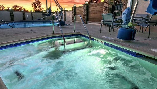 A swimming pool with a clear blue edge, a metal ladder, and a stone wall in the background. - Hampton Inn Cardiff Beach Encinitas, CA Near Del Mar (Cardiff-by-the-Sea)