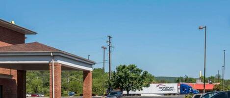 A gas station with a covered parking area, a truck, and a few cars.