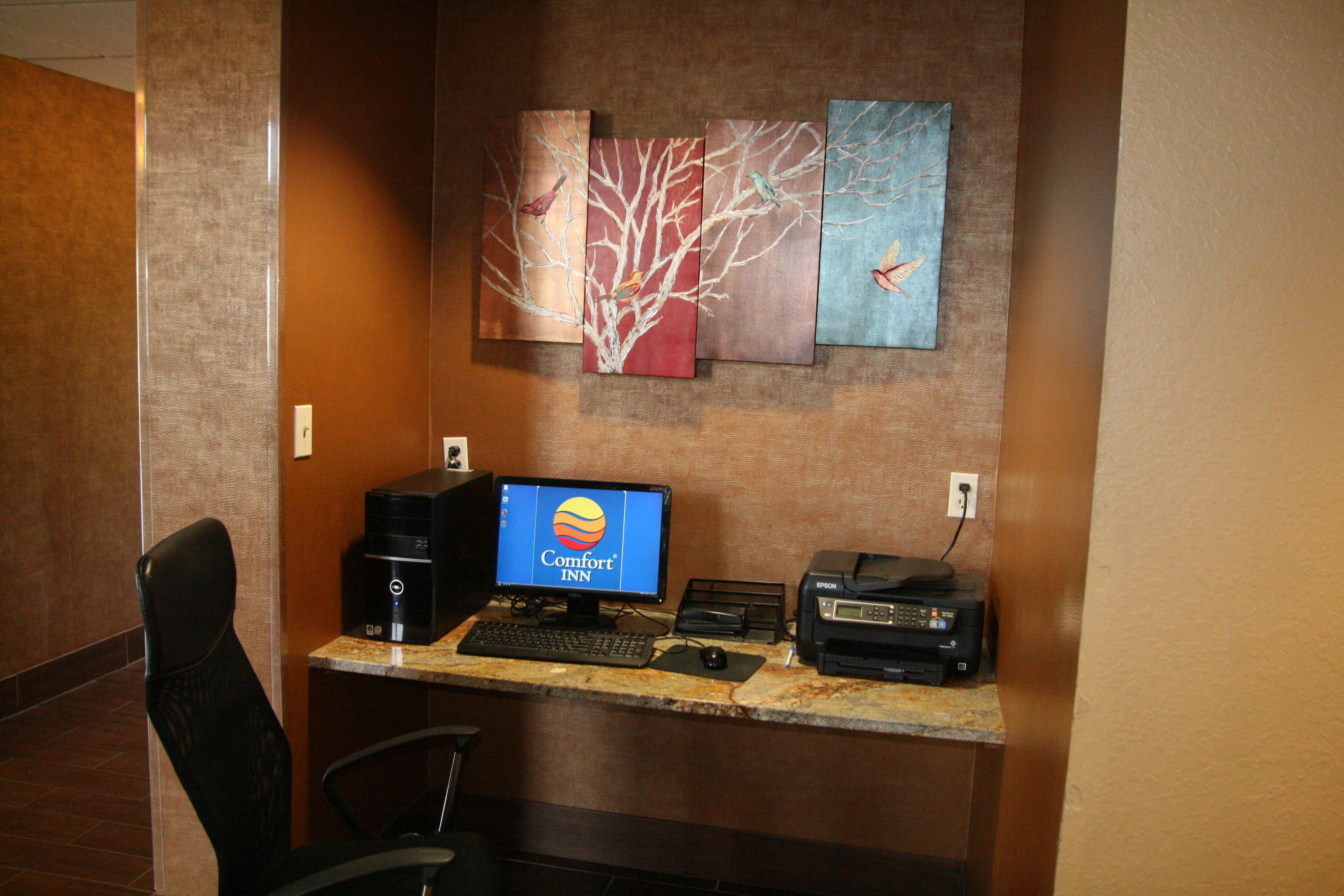 Ein Hotelrezeptionstresen mit Computer, Drucker und einem Kunstwerk an der Wand.