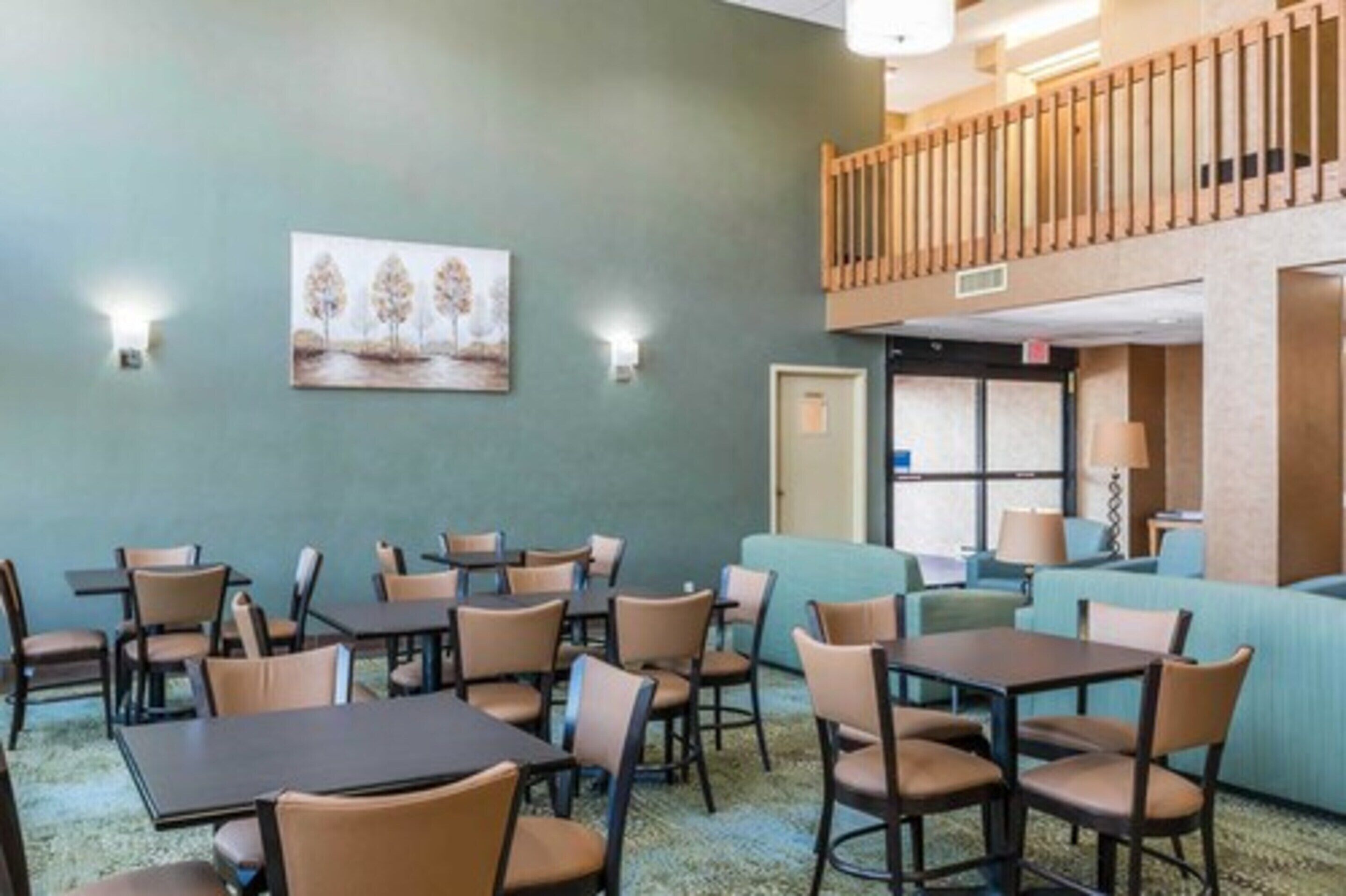 Habitación de hotel con zona de comedor, un cuadro en la pared y un balcón.