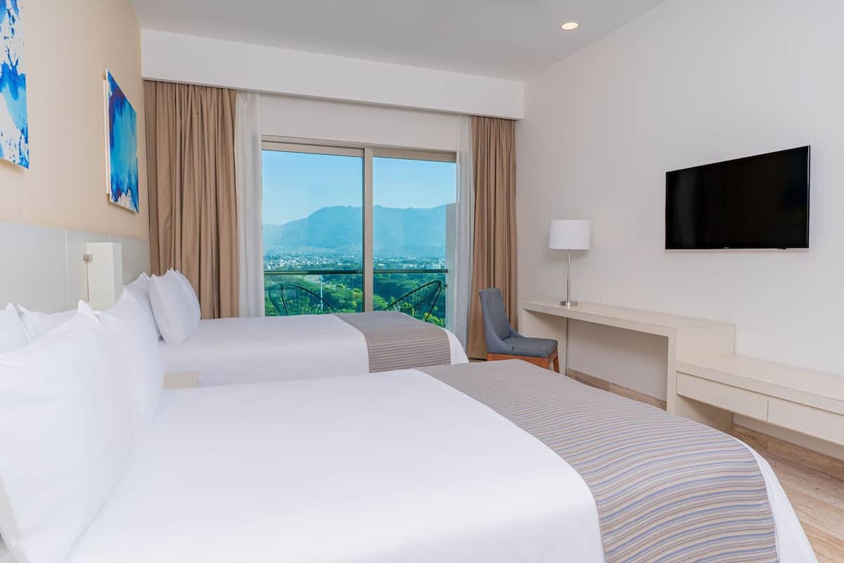 Habitación de hotel con dos camas, televisión, escritorio y una silla.