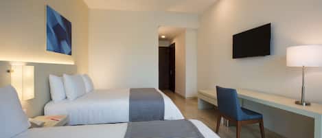 A hotel room with two beds, a desk, a chair, a TV, and a painting on the wall.