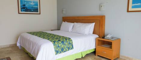 A neatly made bed with a wooden headboard, a bedside table with a phone, and a framed picture on the wall.