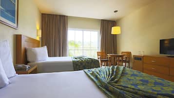 Une chambre d’hôtel avec deux lits, un bureau, une chaise, une télévision et une fenêtre avec des rideaux.
