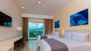 Quarto de hotel com duas camas, uma escrivaninha, uma cadeira, uma TV e uma janela grande com vista para as montanhas.