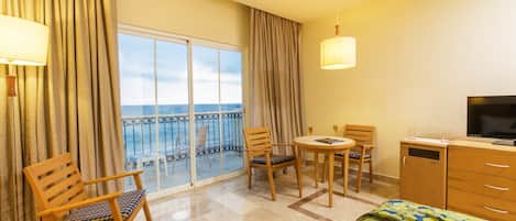 A hotel room with a balcony, a bed, a desk, and a TV.