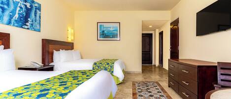 A hotel room with two beds, a desk, a television, and a bathroom.