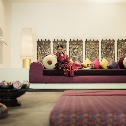 A room with a sofa, decorative pillows, wall art, and a small table with flowers.