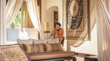 A well-lit room with a sofa, pillows, a lamp, and a large decorative rug.