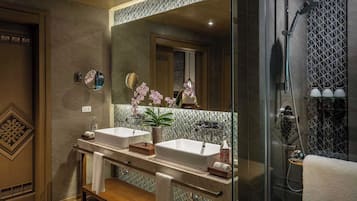 A modern bathroom with two sinks, a large mirror, and a shower area.