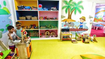 A children's playroom with shelves of toys, a toy kitchen set, and a mural of a farm scene.