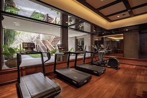 A gym with treadmills, stationary bikes, and a mirrored wall.