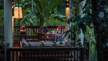 Un espacio al aire libre con mesa y sillas, rodeado de abundante vegetación.