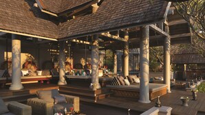 Een terras met rieten meubilair, een bar en een decoratief plafond.