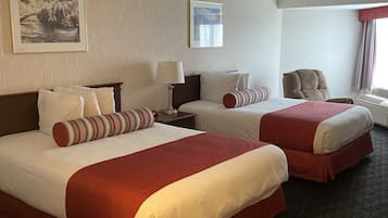 Habitación de hotel con dos camas, un escritorio, una silla y una ventana con cortinas.
