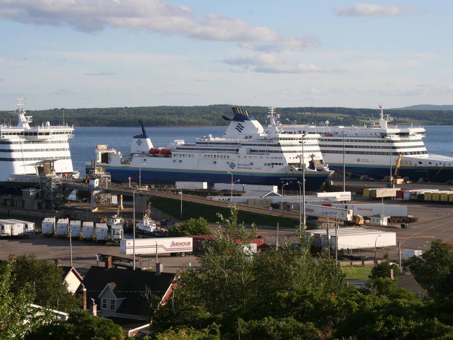 A cruise ship docked at a port with a terminal building and other ships nearby.