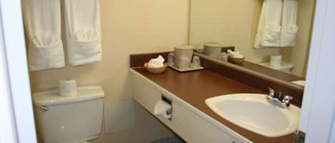 A bathroom with a toilet, sink, and towels.
