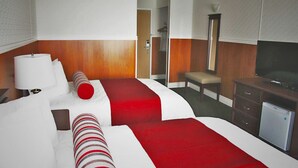 Ein Hotelzimmer mit zwei Betten, einem Schreibtisch, einem Fernseher und einem Spiegel.