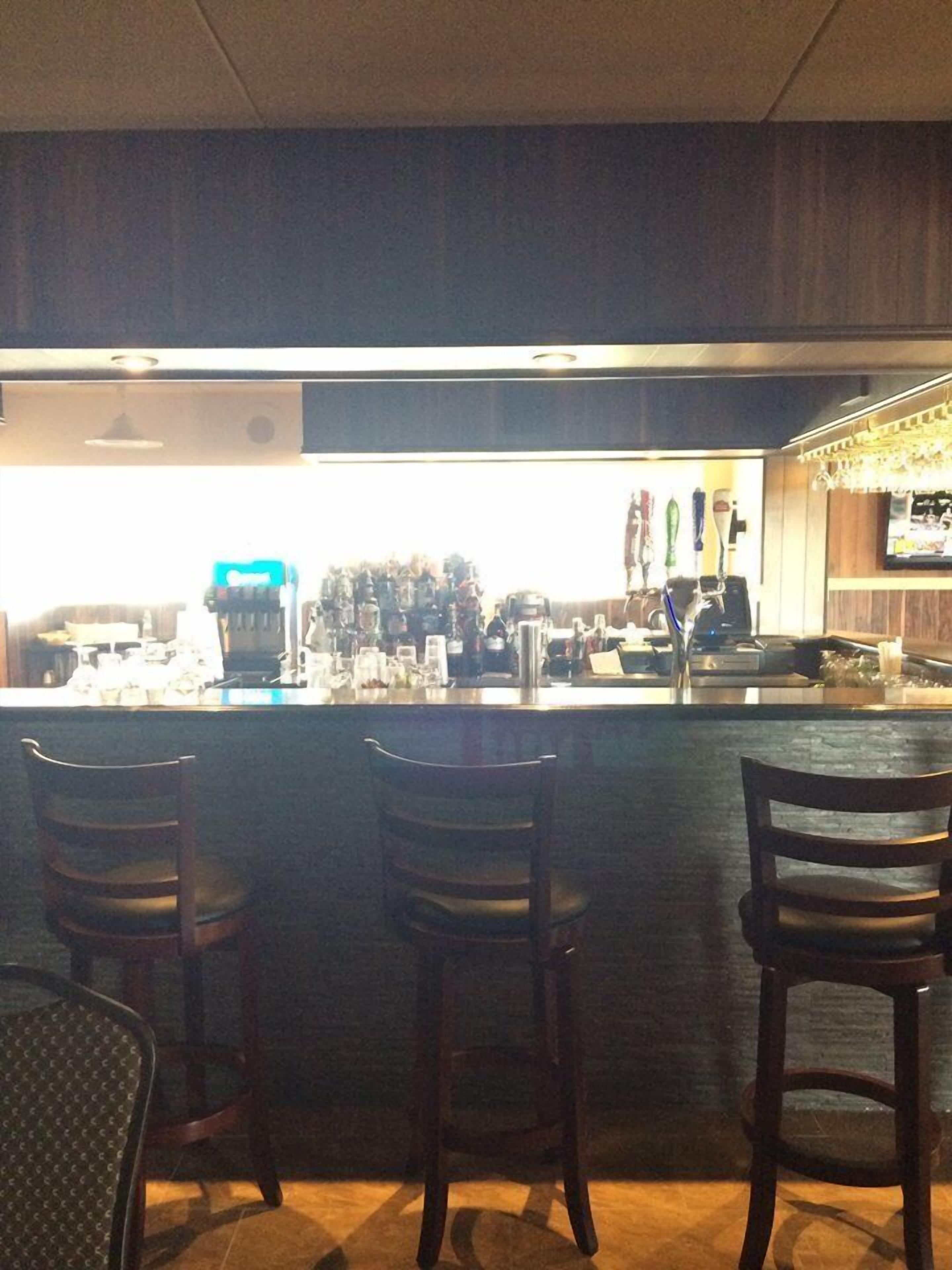 A bar area with a counter, bar stools, and a television screen.
